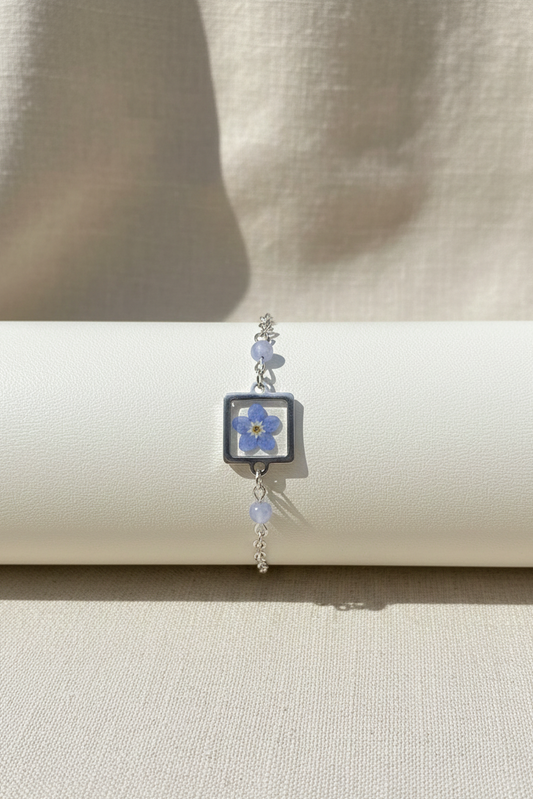 Bracelet with a blue flower charm on a beige background