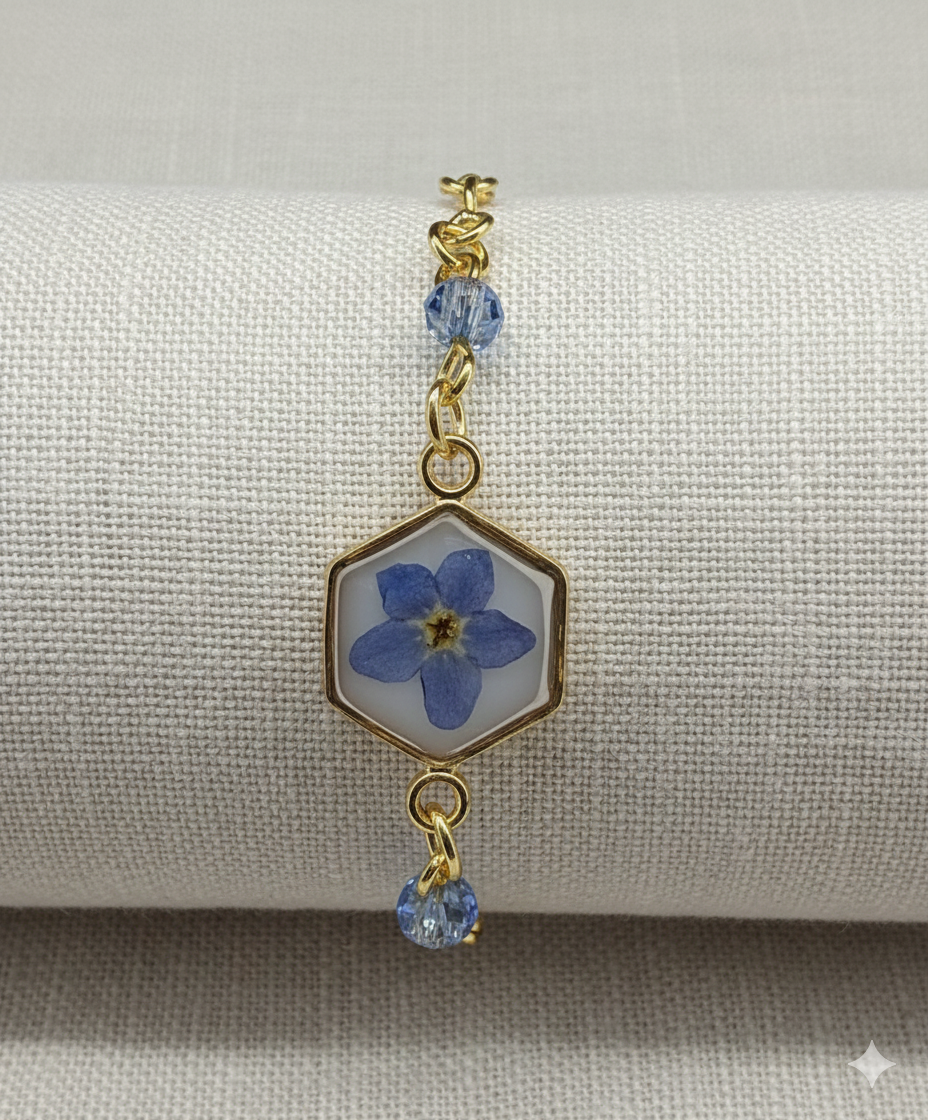 Bracelet with blue flower charm and gold accents on a gray background