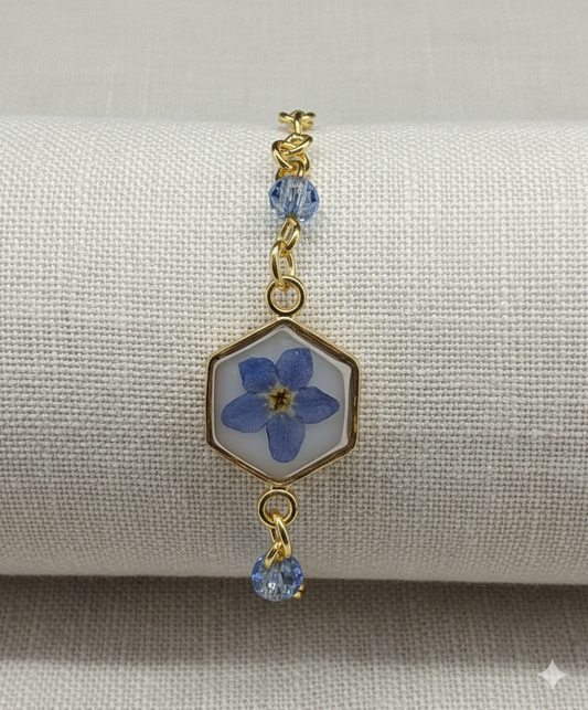 Bracelet with blue flower charm and gold accents on a gray background