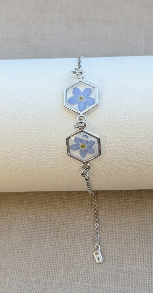 Silver bracelet with floral hexagonal charms on a beige background