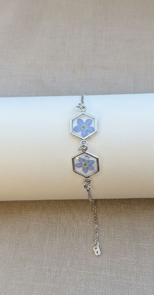 Silver bracelet with floral hexagonal charms on a beige background