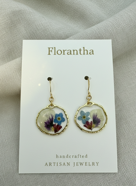 Florantha earrings with floral design on a card against a textured gray background