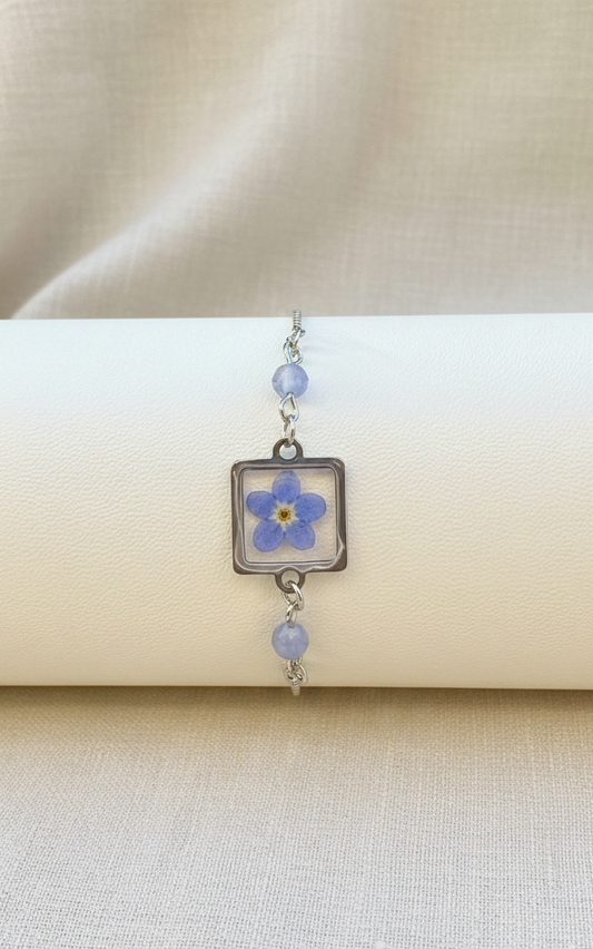 Bracelet with a blue flower charm on a beige background