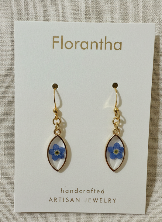 Florantha earrings with blue floral elements on a white card