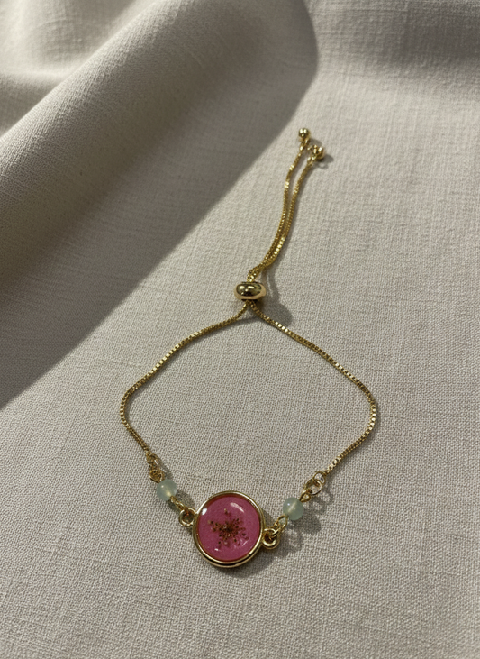 Gold bracelet with a pink gemstone on a light fabric background