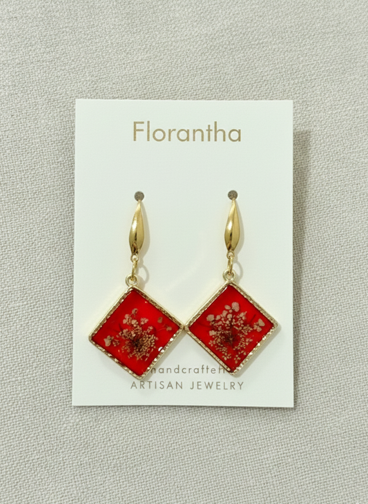 Red square earrings with gold accents on a Florantha branded card.