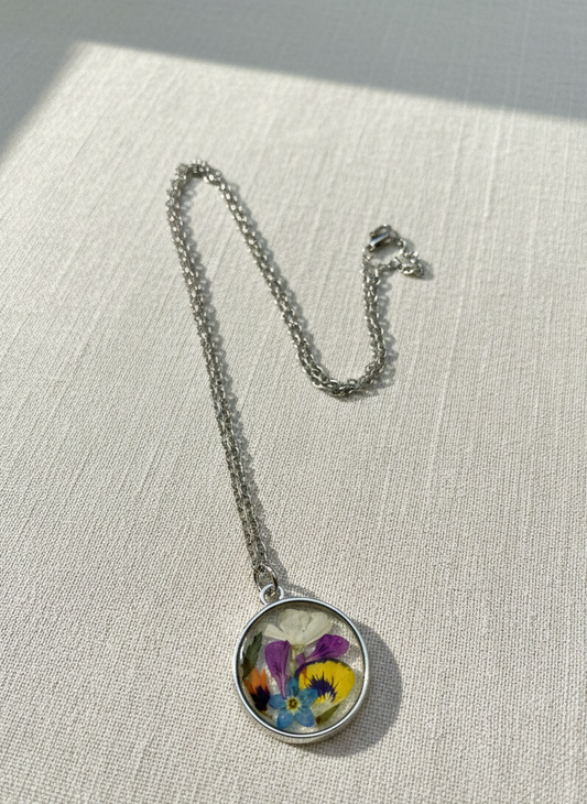 Necklace with a pendant featuring pressed flowers on a textured surface